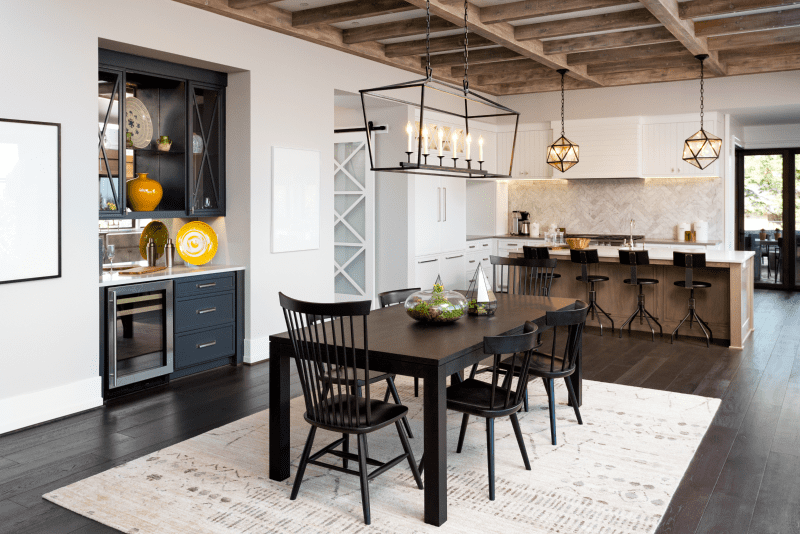 Dining Room and Kitchen In New Farmhouse Style Luxury Home with Elegant Pendant Light Fixtures and Open Concept Floor Plan Design. Features Cross Hatch Wooden Beam Ceiling